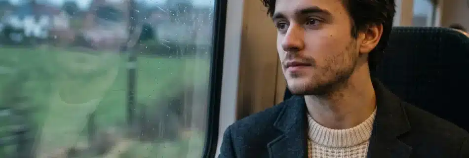 Osken sitting beside a rain-speckled train window and looking across the passing countryside