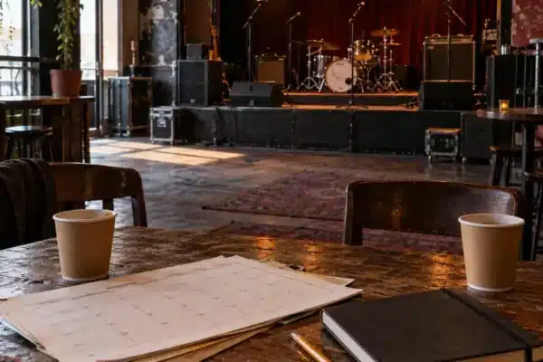 An empty grassroots music venue with a booking calendar and notebook on a wooden table before a show